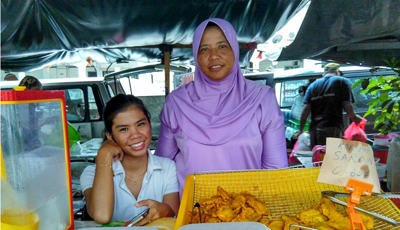 Two women at a market stall selling food and drinks